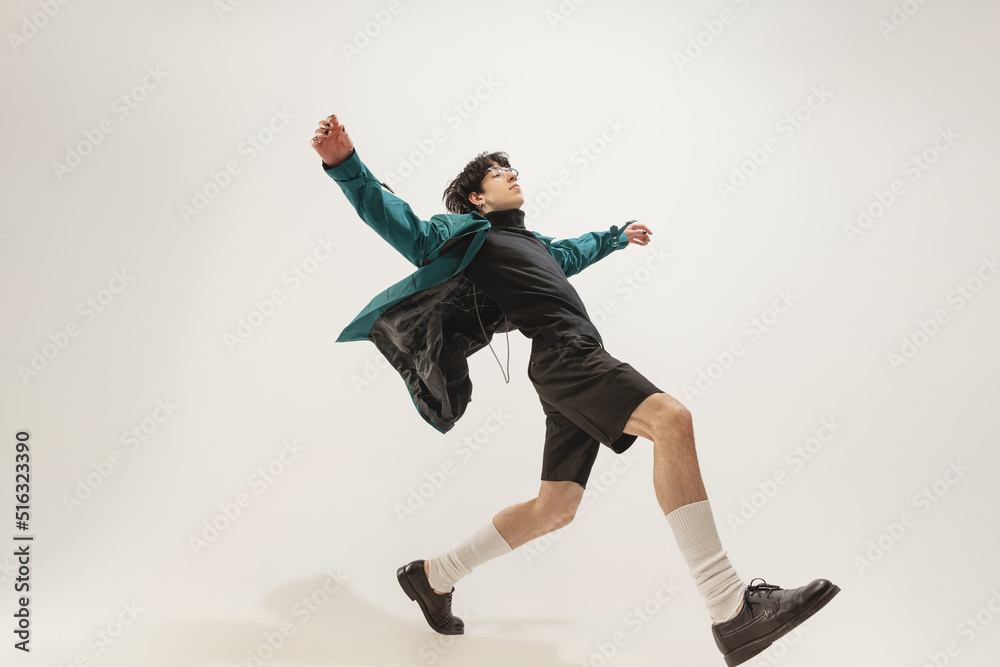 Fototapeta premium Portrait of young expressive man in stylish outfit posing isolated over grey studio background