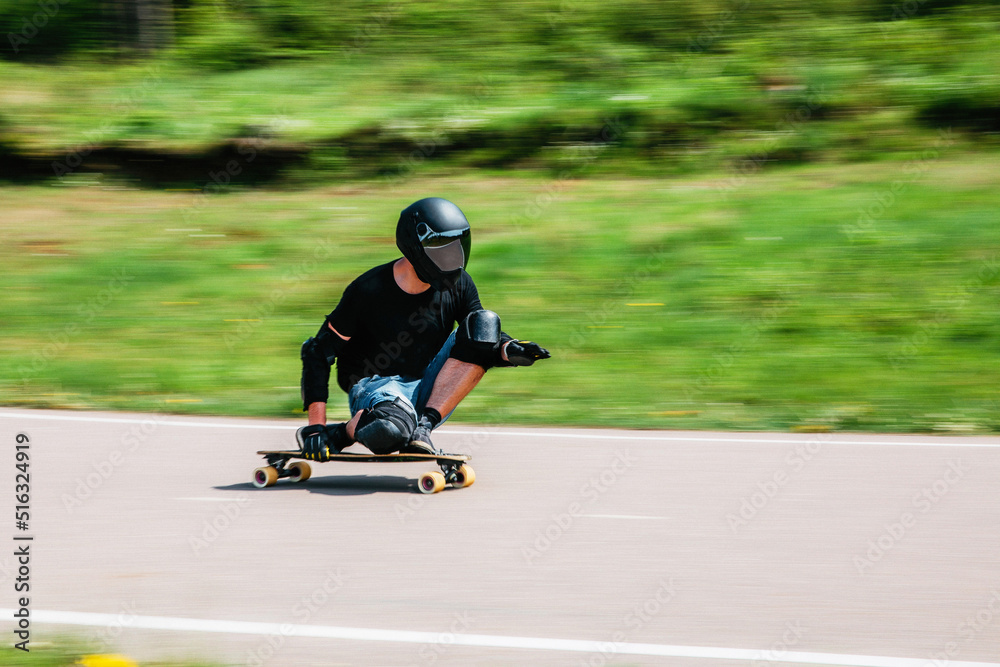 Young sporty man on a longboard rides at high speed down the track