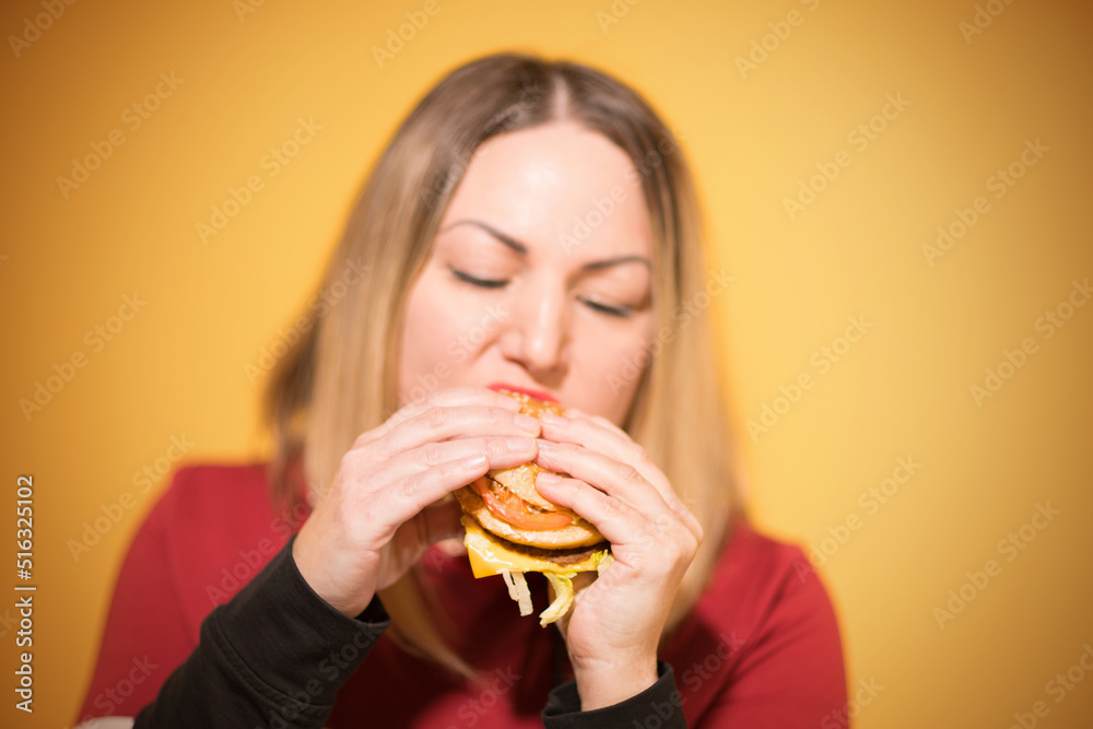 A hungry woman is biting a big tasty burger A hungry woman is biting a big tasty burger