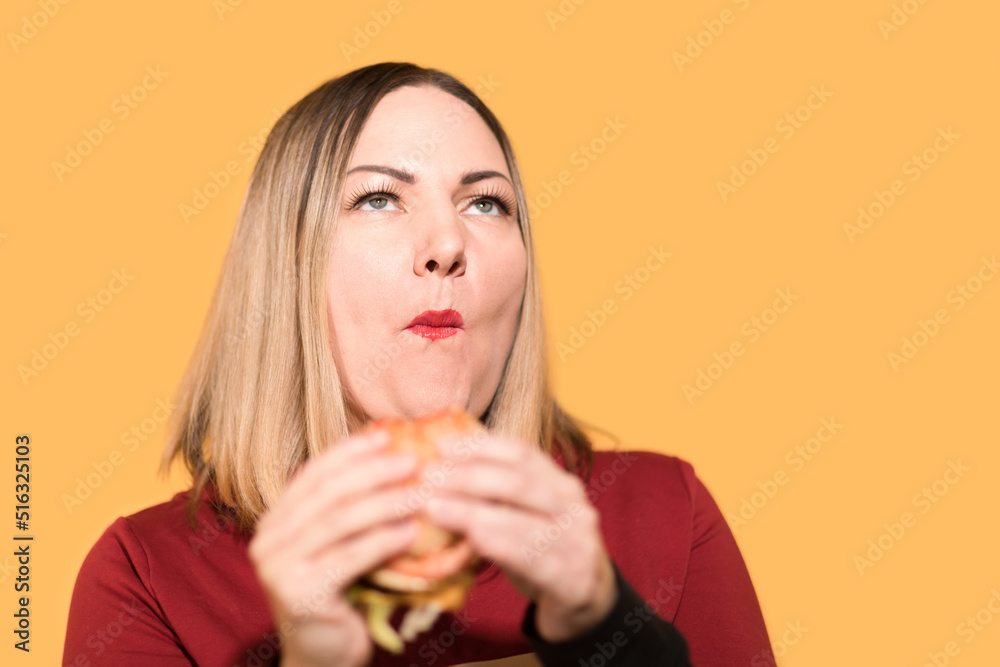 A hungry woman is biting a big tasty burger A hungry woman is biting a big tasty burger