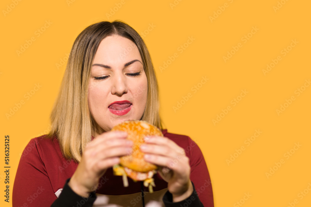 A hungry woman is biting a big tasty burger A hungry woman is biting a big tasty burger