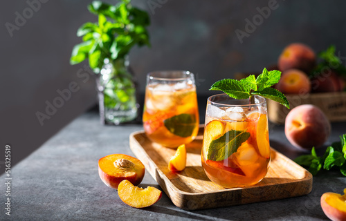 Принти на полотні Refreshing iced tea with ripe peaches on dark background