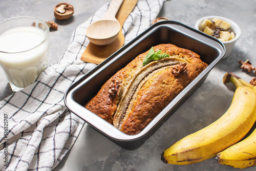 Banana bread or cake in metal baking form on concrete table. Delicious homemade dessert or morning breakfast.