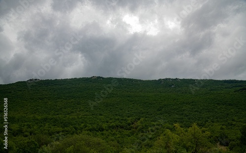 dramatic clouds hanging over the range of a green mountain forest photo