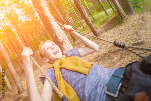 Cheerful laughing boy on a swing in the park. Joy, freedom