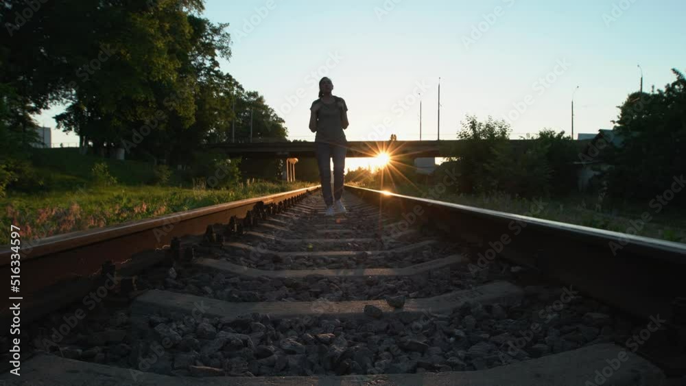 A beautiful elderly woman walks along the railroad and balances on the rails. A beautiful elderly woman walks along the railroad and balances on the rails.