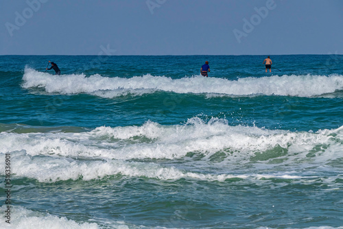 Surfers in the water on the waves of the Mediterranean Sea.