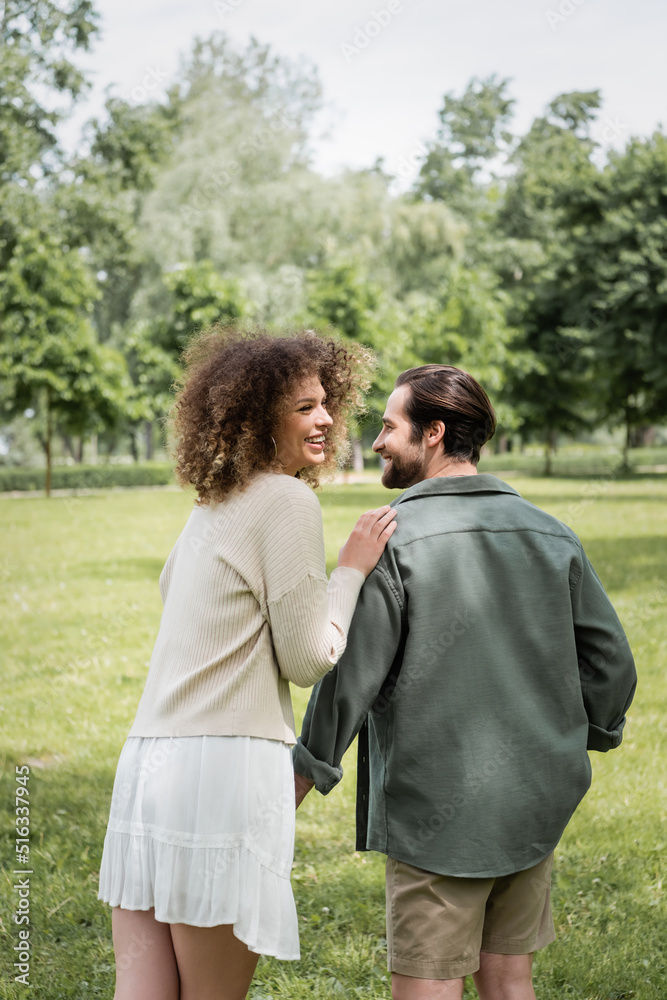 Fototapeta premium curly woman in dress and man in summer clothes having date in park.