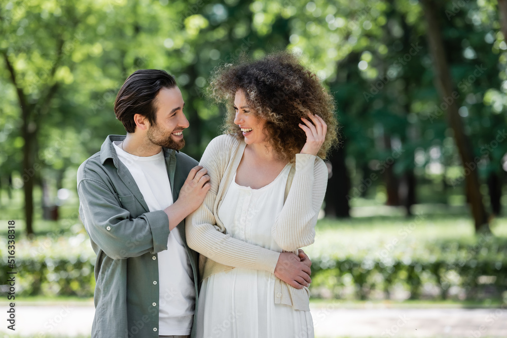 joyful young couple smiling and looking at each other in summer park. joyful young couple smiling and looking at each other in summer park.