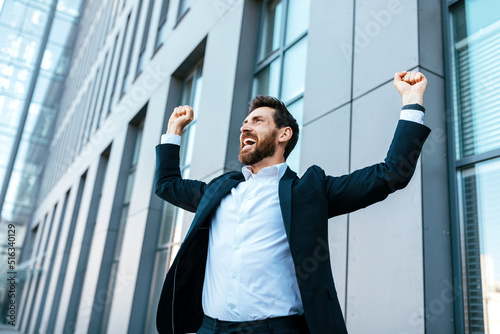 Happy satisfied excited european millennial bearded businessman in suit rejoices in successful deal or win