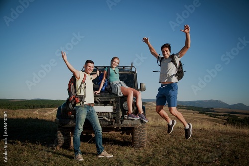 Young happy adult friends on a hike with a car