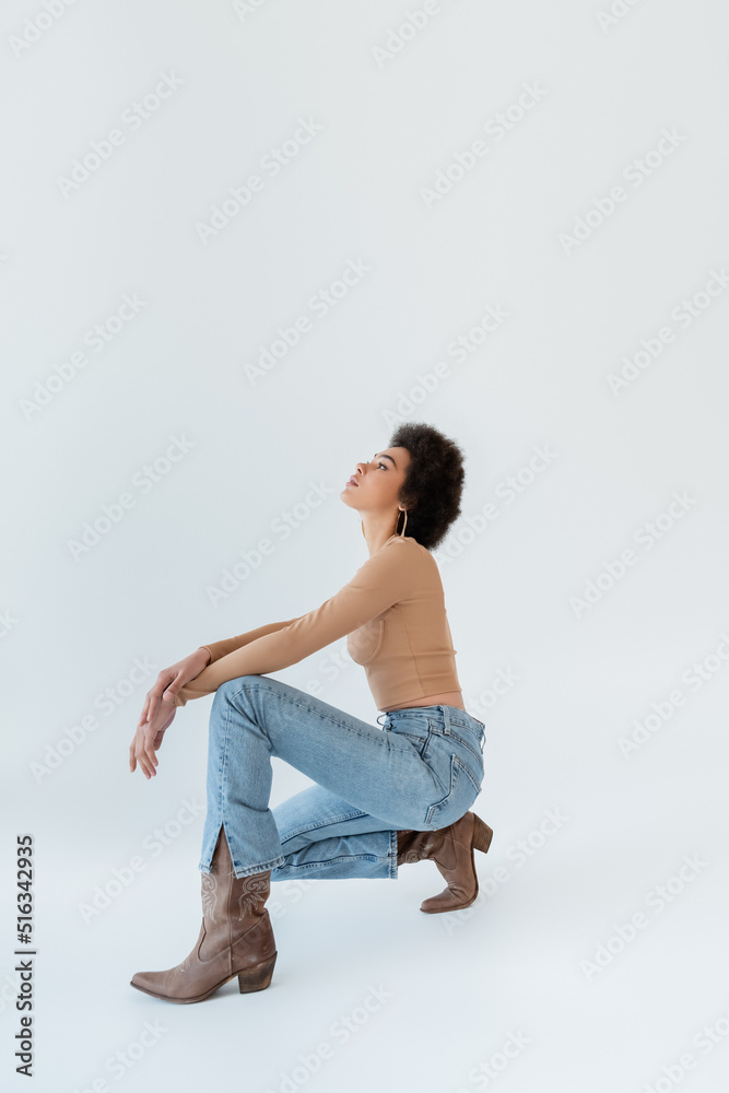 side view of african american model in jeans and cowboy boots on grey background. side view of african american model in jeans and cowboy boots on grey background.