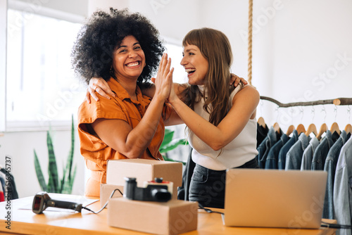 Foto Cheerful thrift store owners high fiving each other in their shop