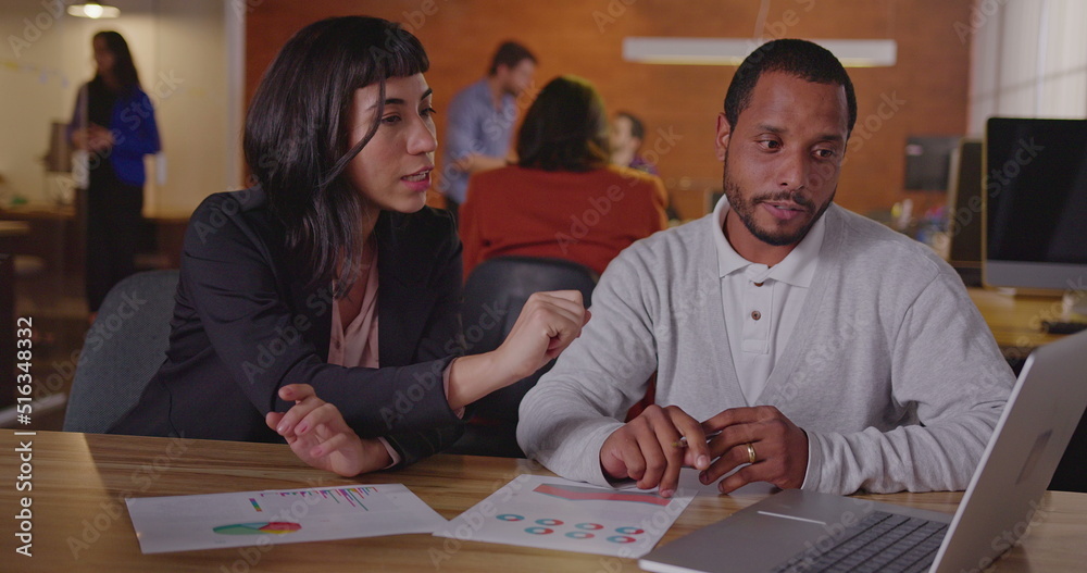Fototapeta premium Diverse colleagues discussing work. A black employee explaining new job for a latin hispanic female staff