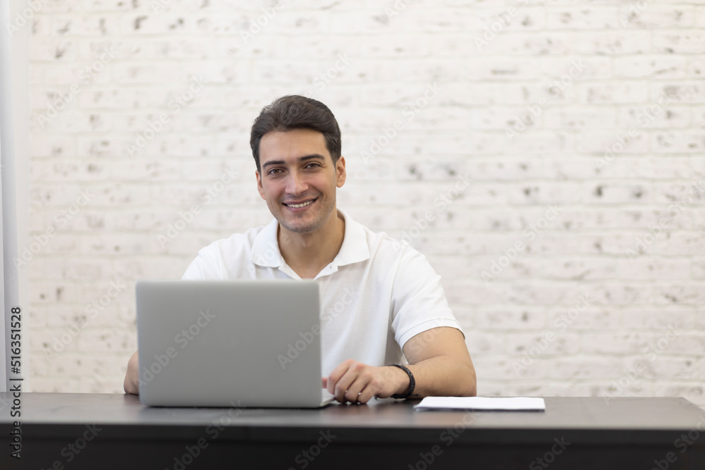 Portrait of smiling young businessman working on laptop at home. Distant work concept Portrait of smiling young businessman working on laptop at home. Distant work concept