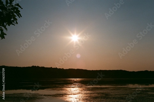 Breathtaking sunset over a calm lake and evergreen hills in Mendon Ponds Park, Rochester, New York photo