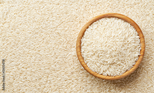 wooden plate with basmati rice on a long rice background close-up top view.