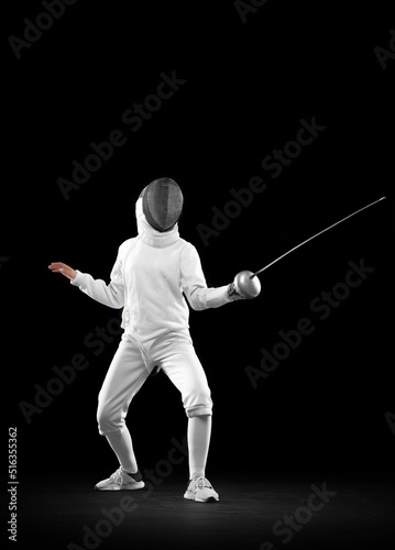 Sportive girl, female fencer in white fencing costume and mask in action, motion isolated on dark background. Sport, youth, activity, skills, achievements, goal.