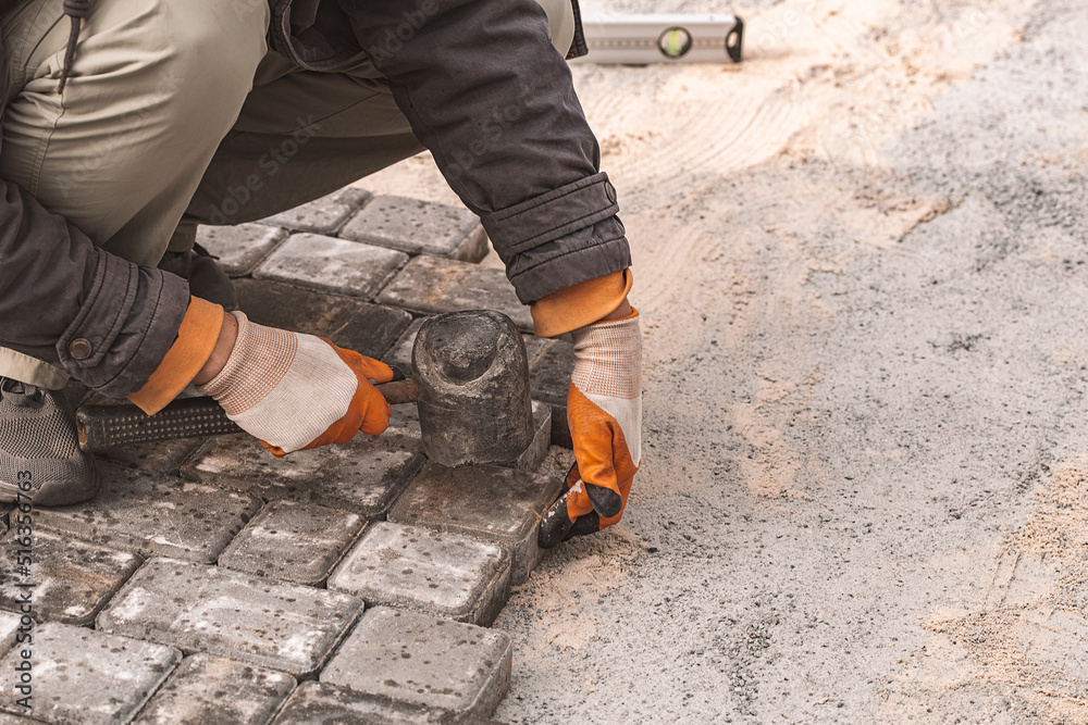 Laying paving slabs close-up. Road surface, construction. Sidewalk repair. Worker laying stone paving slab. Laying tiles in the city park garden . Manual fixed tessellated paving slabs Laying paving slabs close-up. Road surface, construction. Sidewalk repair. Worker laying stone paving slab. Laying tiles in the city park garden . Manual fixed tessellated paving slabs