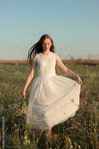 Romantic woman dancing in a wonderful flower field. Warm sunset colors © Тамара Печеная