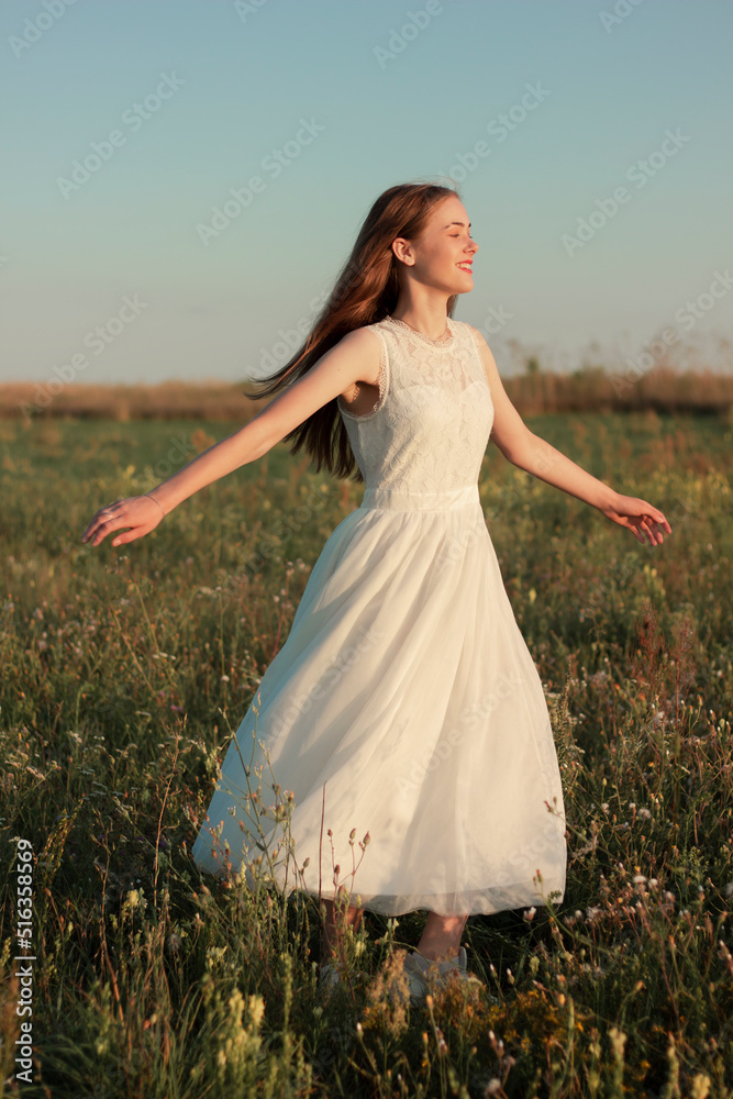 Fototapeta premium Romantic woman dancing in a wonderful flower field. Warm sunset colors