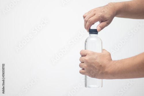Man's hand holds a plastic water bottle to open the lid.