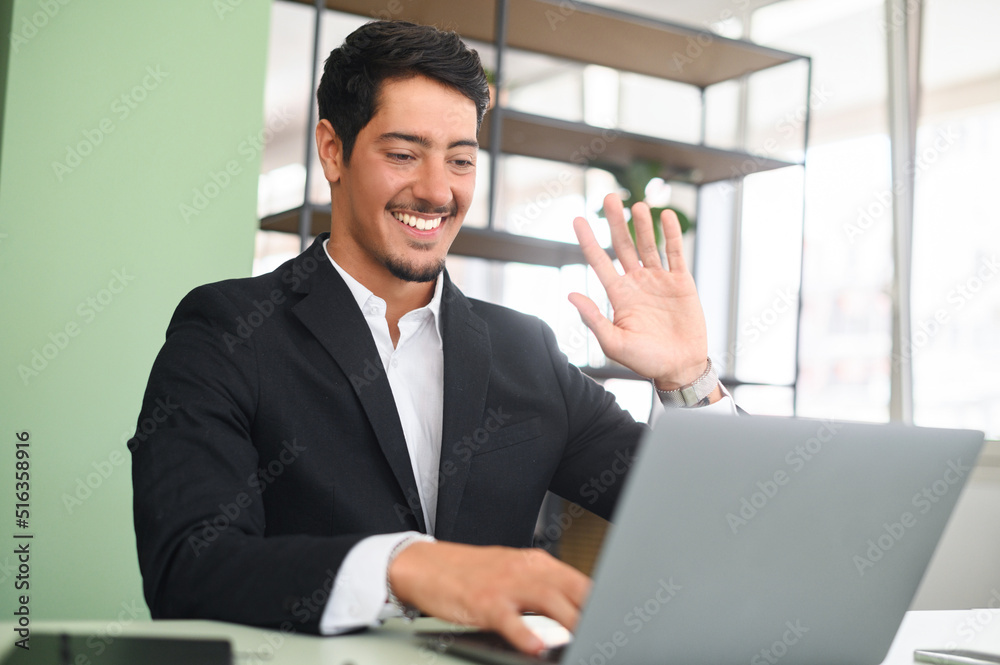 Young latin businessman entrepreneur in business wear talking online, discussing project, gesturing, presenting new business idea to client, team or to investor online on video call via laptop Young latin businessman entrepreneur in business wear talking online, discussing project, gesturing, presenting new business idea to client, team or to investor online on video call via laptop