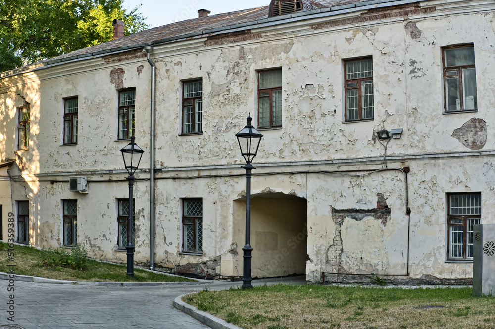 The fragment of the old building facade. Cracks on the plaster and broken windows. Emergency residential building. Old two-story house with an arch. The fragment of the old building facade. Cracks on the plaster and broken windows. Emergency residential building. Old two-story house with an arch.