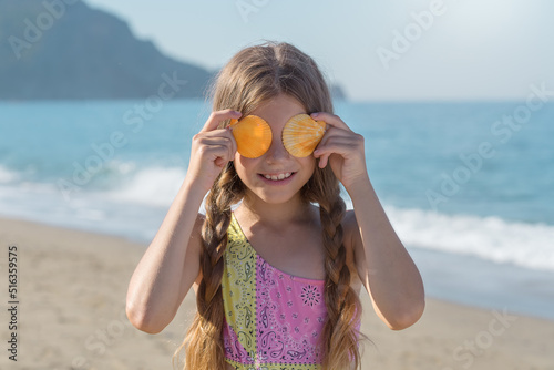 A 9-year-old child holds seashells against the backdrop of the sea.