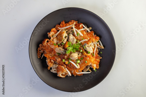 Hot pan of crispy fried oyster omelette served with bean sprout and spicy sauce.