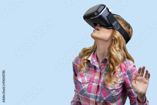 Young casual woman uses virtual glasses on color background. Space for text. © DenisProduction.com