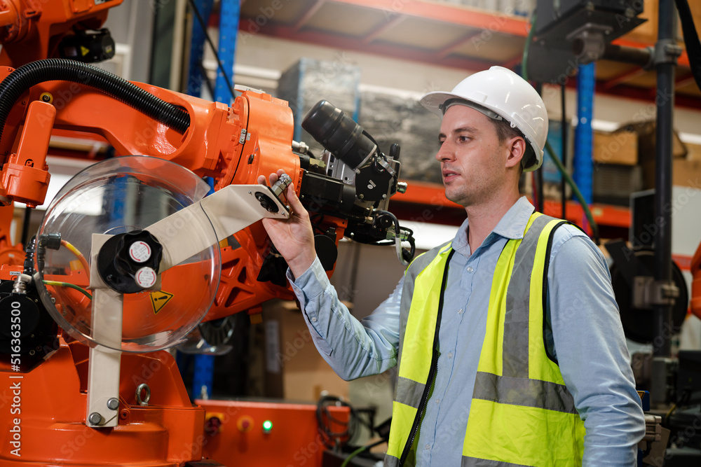 Male engineer checking and inspection control a robot arm machine welding steel in an industrial factory, Fast and highly secure. Male engineer checking and inspection control a robot arm machine welding steel in an industrial factory, Fast and highly secure.