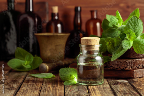 Fresh spearmint leaves and a small bottle with essential mint oil. photo