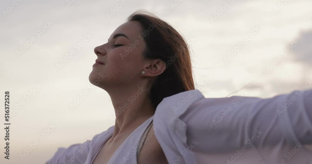 Freedom, young woman relaxing with raised hands against overcast sky background, slow motion Freedom, young woman relaxing with raised hands against overcast sky background, slow motion
