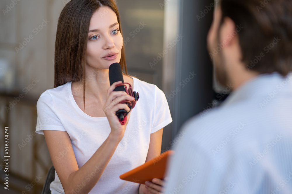 Pretty young journalist interviewing a famous person in a studio Pretty young journalist interviewing a famous person in a studio