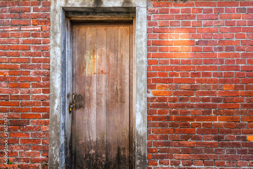 A old locking wooden door with the red brick wall. photo