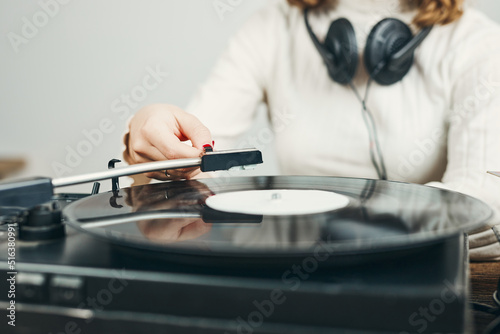 Young woman listening to music from vinyl record player. Playing music on turntable player. Female enjoying music from old record collection at home