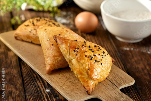 aditional uzbek pastry - samsa with meat. Uzbek pies with meat and puff dough on wooden background in rustic style. Meat samosa with ingredients. East pastry. photo