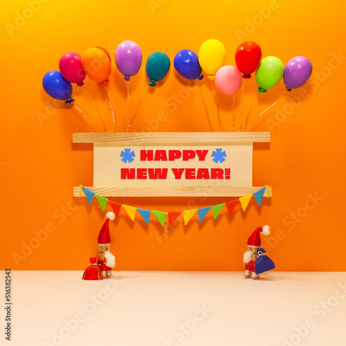 Festive sign decorated balloons  garland of flags. Two clothespin Santa Claus toys with bags of gifts. Message Happy New Year.