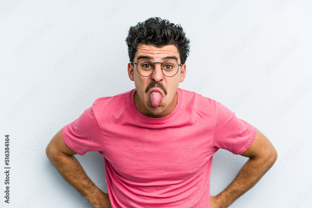 Young caucasian man isolated on blue background funny and friendly sticking out tongue. Young caucasian man isolated on blue background funny and friendly sticking out tongue.
