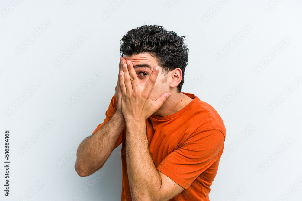 Young caucasian man isolated on blue background blink through fingers frightened and nervous. Young caucasian man isolated on blue background blink through fingers frightened and nervous.