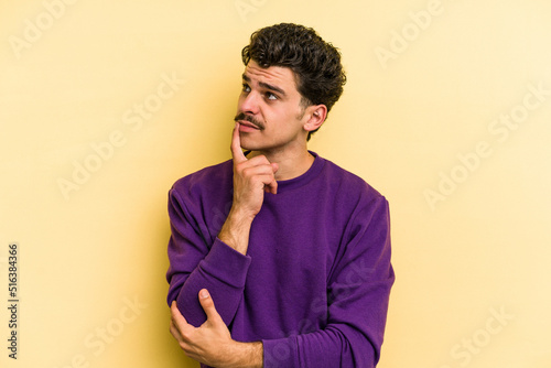 Young caucasian man isolated on yellow background contemplating, planning a strategy, thinking about the way of a business.