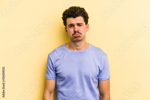 Young caucasian man isolated on yellow background sad, serious face, feeling miserable and displeased.