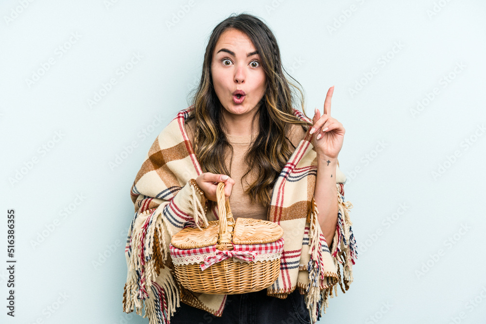 Young caucasian woman holding a picnic basket isolated on blue background having some great idea, concept of creativity.