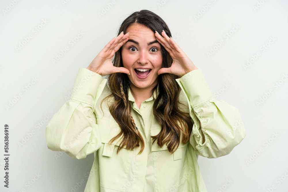 Naklejka premium Young caucasian woman isolated on white background receiving a pleasant surprise, excited and raising hands.