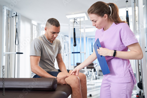 Woman doctor examining male patient leg in clinic