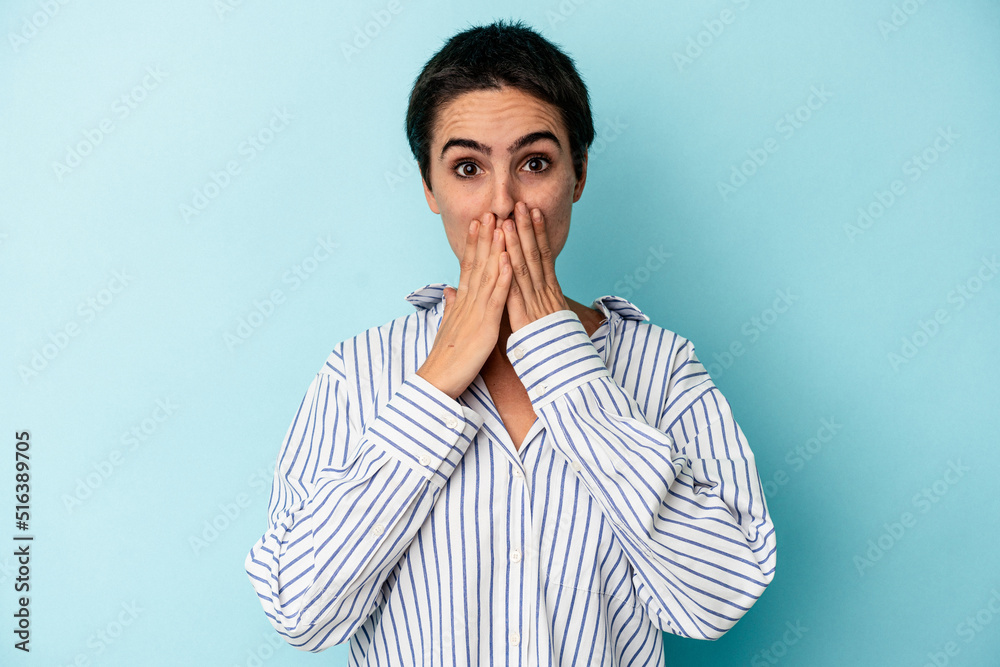 Young caucasian woman isolated on blue background shocked covering mouth with hands. Young caucasian woman isolated on blue background shocked covering mouth with hands.