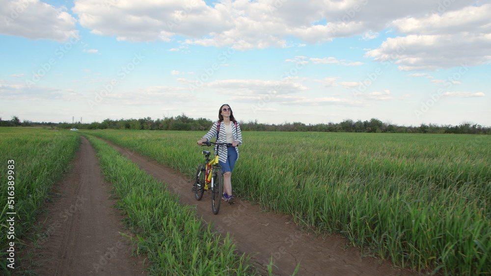 4K. A young woman walks with a bicycle through a field 4K. A young woman walks with a bicycle through a field