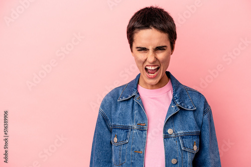 Young caucasian woman isolated on blue background shouting very angry, rage concept, frustrated.