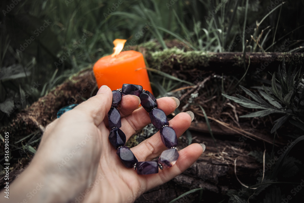 burning candles and a womans hand with a bracelet on a dark natural background. pagan wiccan, slavic traditions. Witchcraft, esoteric spiritual ritual for mabon,  samhain. autumn equinox festival